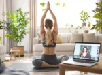 Femme pratiquant le yoga chez elle devant un ordinateur portable