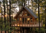 Cabane perchée éclairée dans une forêt française au coucher du soleil